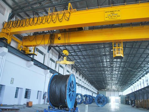cẩu trục màu vàng đang di chuyển trên đường ray làm bằng thép I màu xám trong một nhà máy